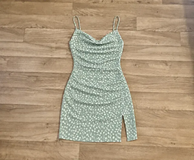 Sage-green patterned dress laid flat on a wooden floor before creating content